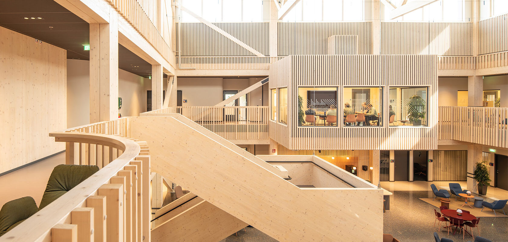 Modern wooden office interior with open spaces, large windows, staircase, and meeting rooms.