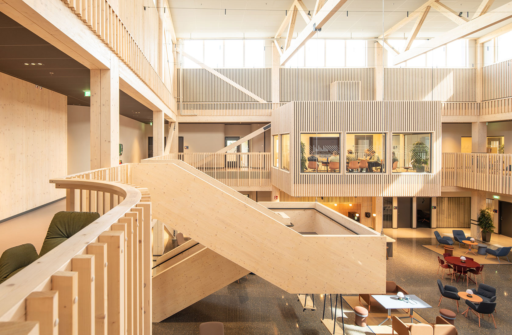 Modern wooden office interior with open spaces, large windows, staircase, and meeting rooms.