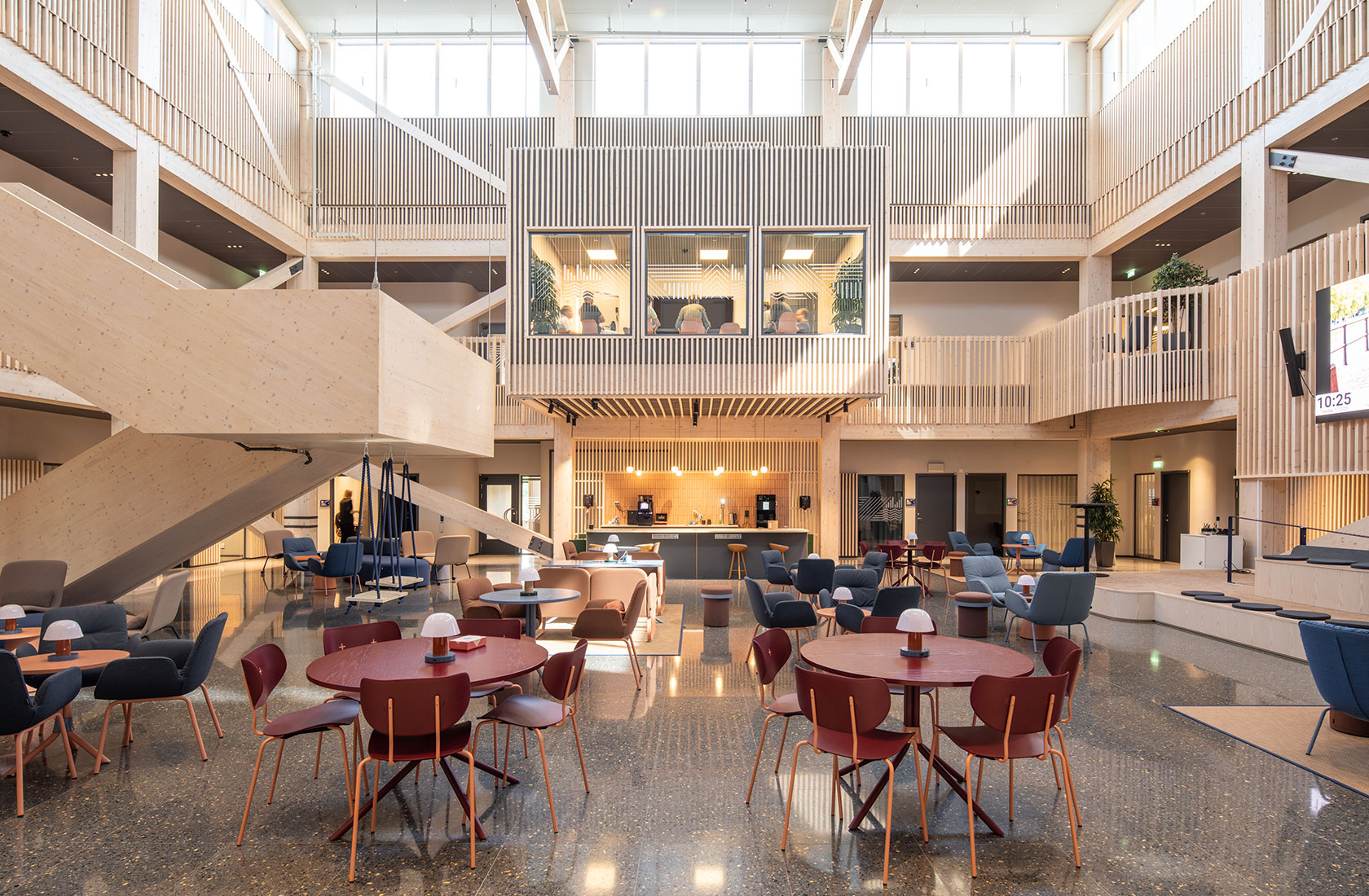 Modern open workspace with wooden interior, multiple seating areas, and a central coffee station.