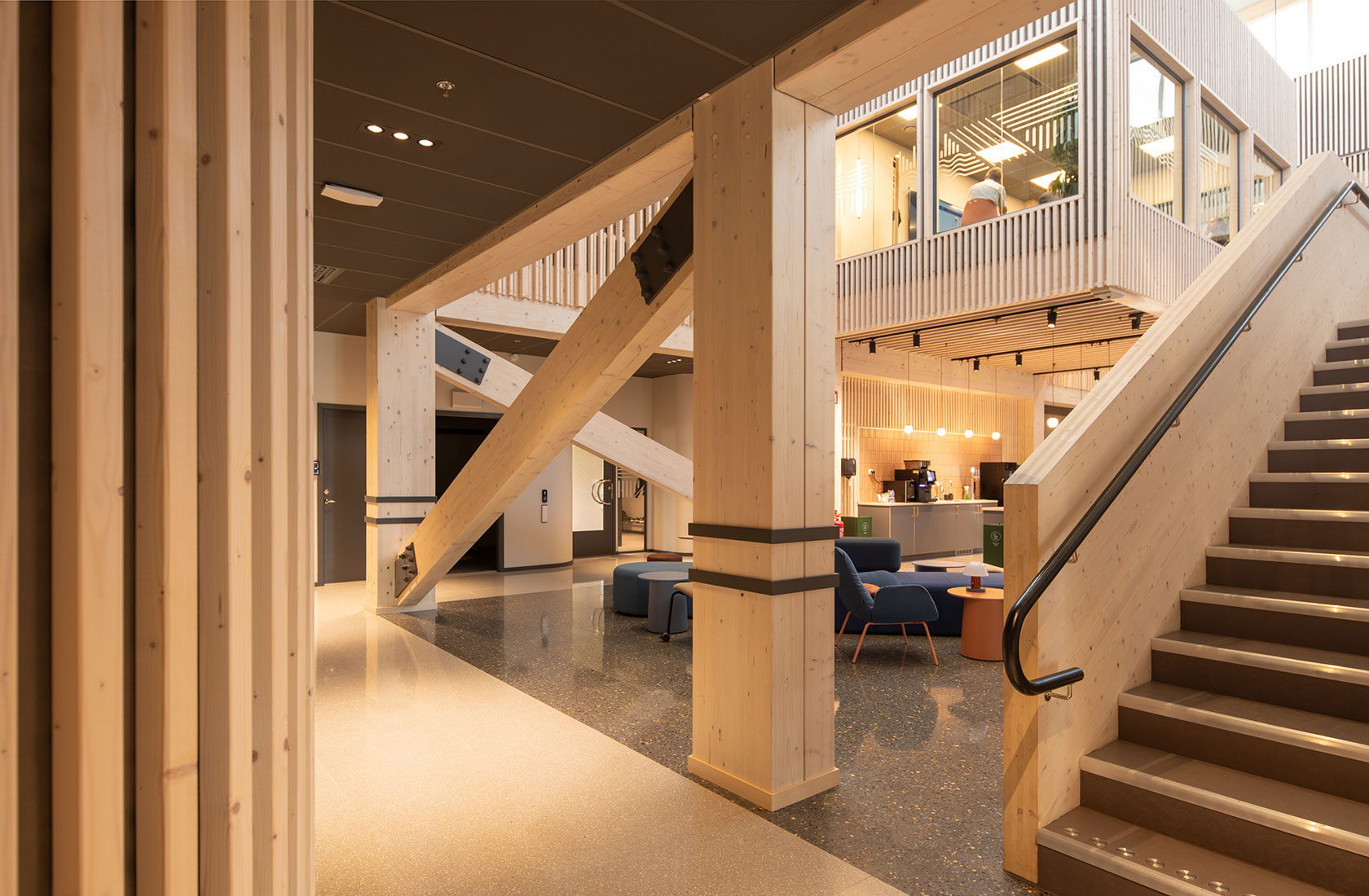 Modern wood-themed interior with staircase and seating area in contemporary office environment.