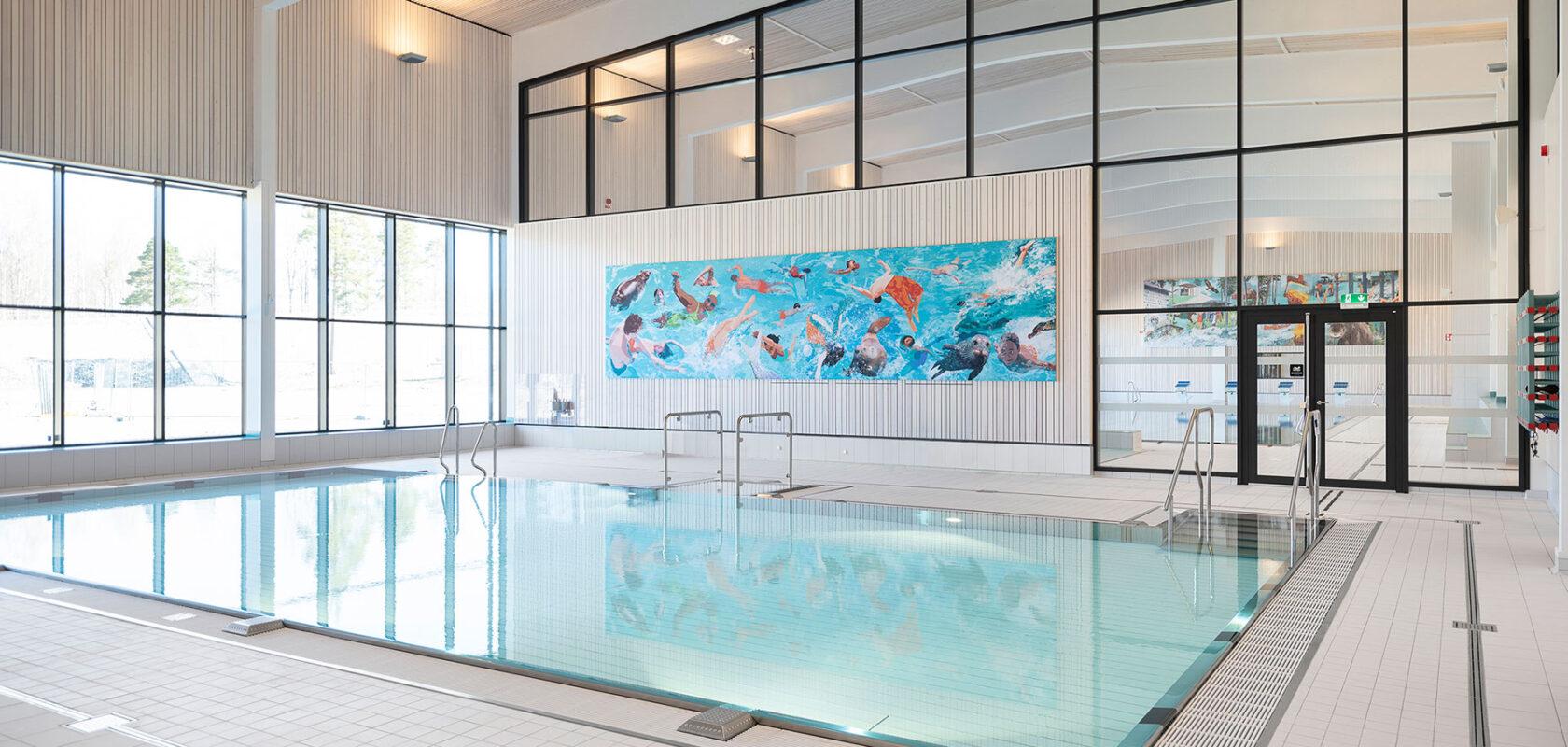 Modern indoor swimming pool with large windows and colorful artwork on the far wall.