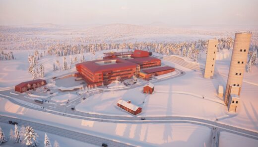 Modern red hospital building in snowy forest landscape with tall observation towers and access roads