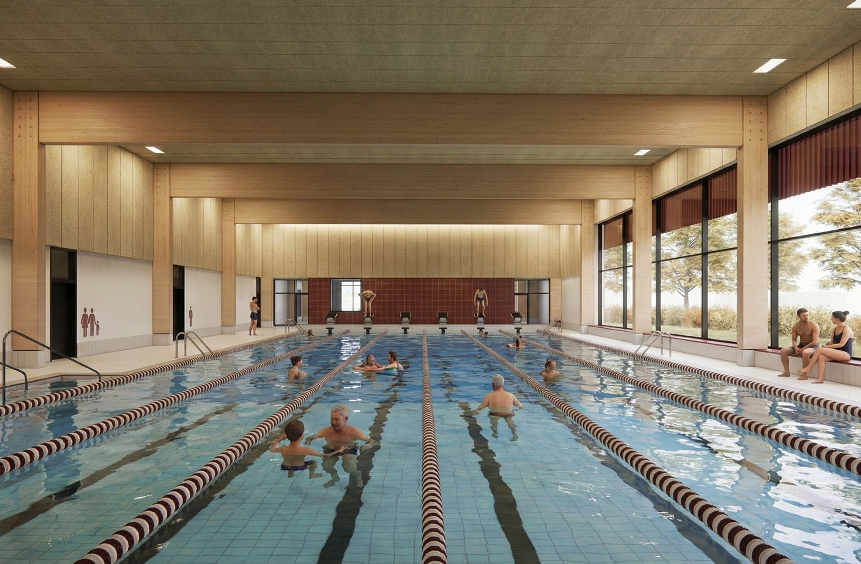 Indoor lap swimming pool with people exercising in lanes and relaxing by the deck