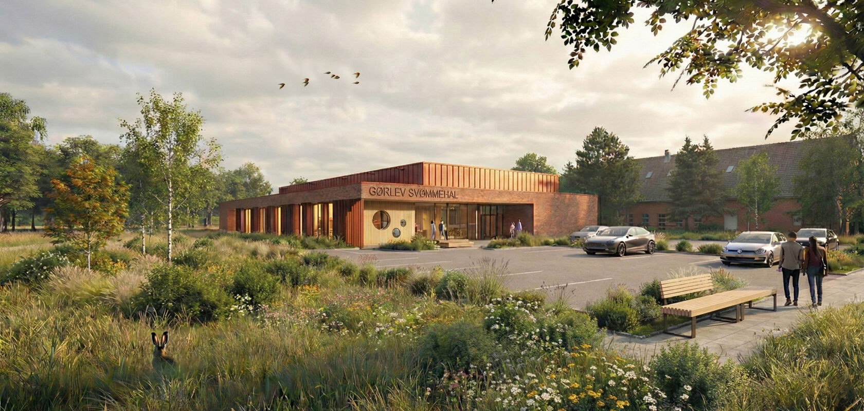 Modern Gorlev swimming hall surrounded by greenery and parking lot at sunset