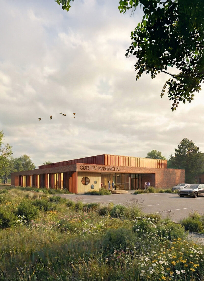 Modern brick and wood swimming hall surrounded by greenery and parking lot
