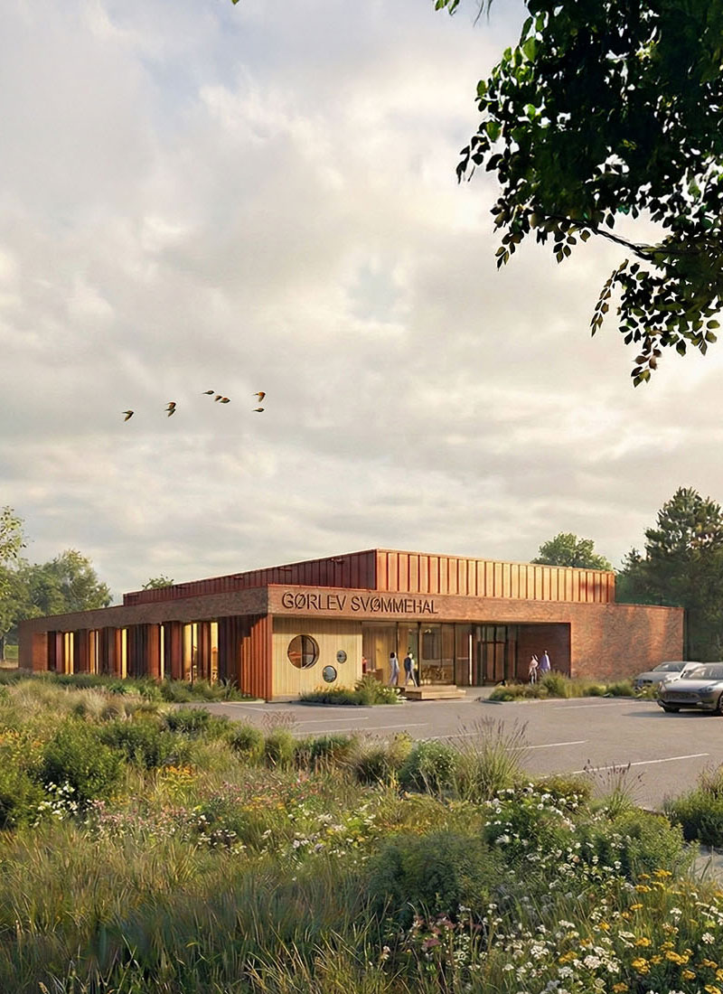 Modern brick and wood swimming hall surrounded by greenery and parking lot
