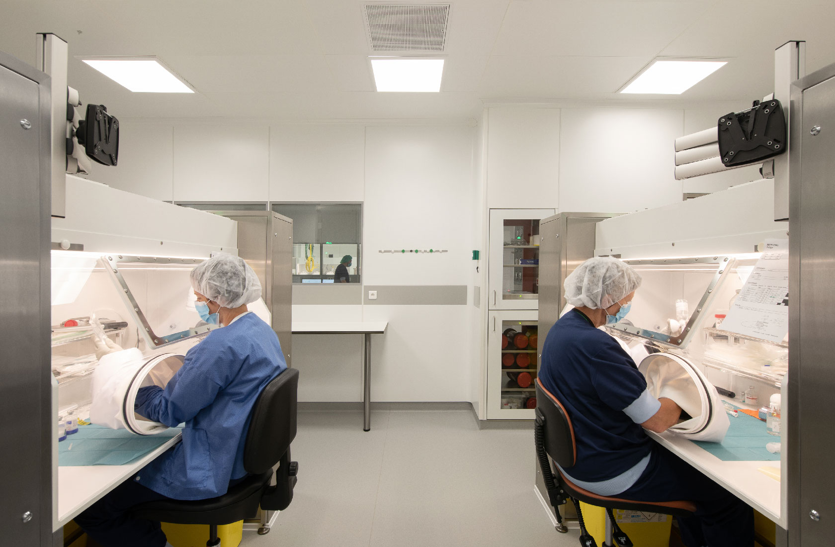 Technicians working in sterile hospital laboratory cleanroom using glovebox workstations