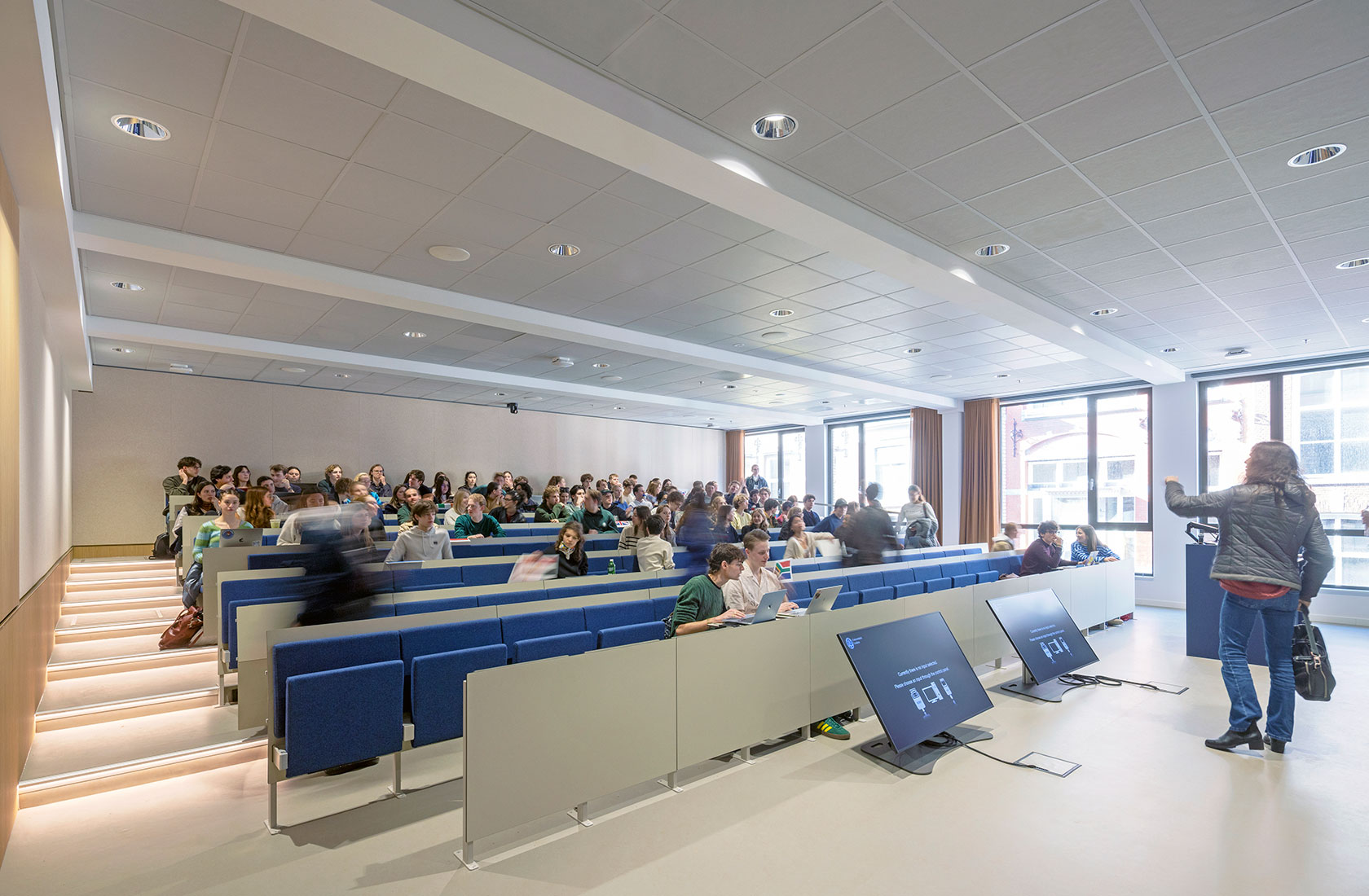 University lecture hall with students seated and instructor presenting at front