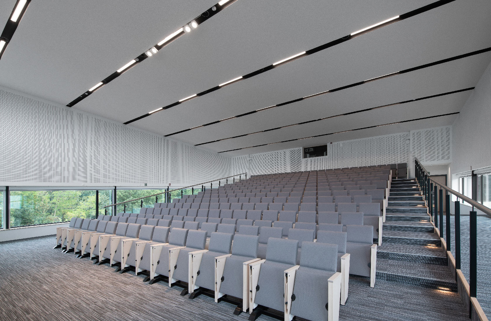 Modern empty lecture hall with tiered seating and large windows in hospital auditorium