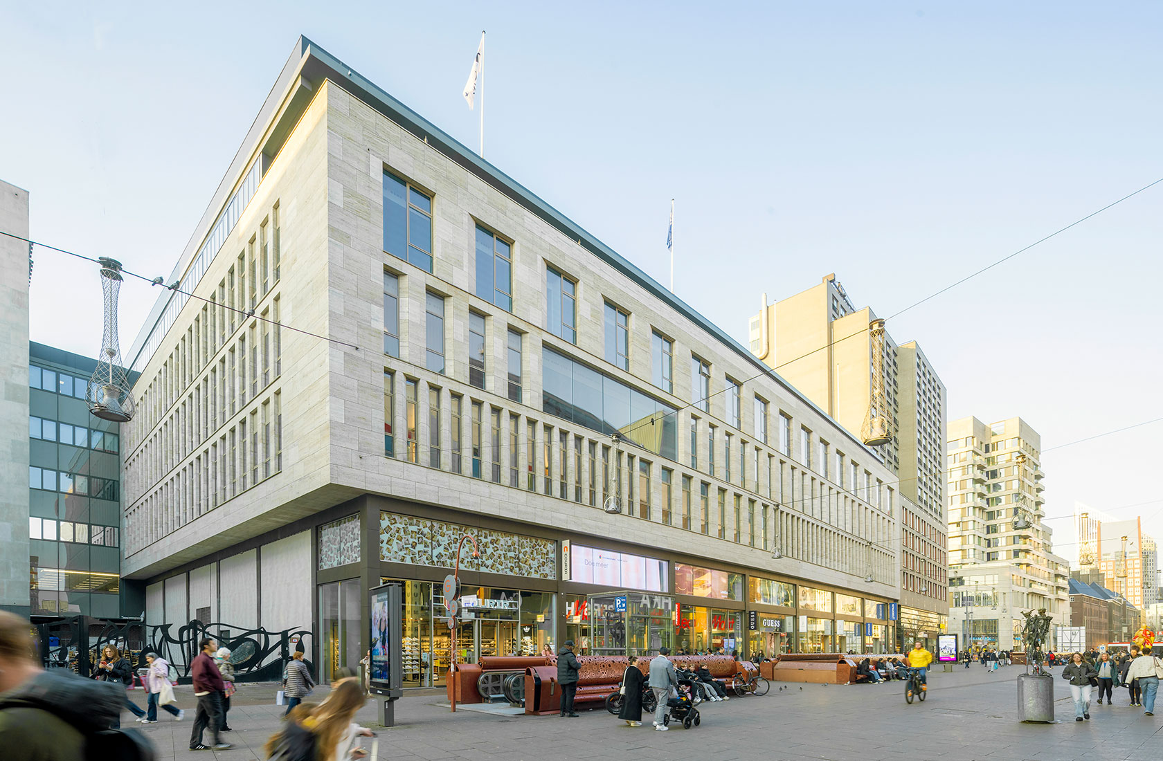 Modern university center building on busy city square with pedestrians and storefronts