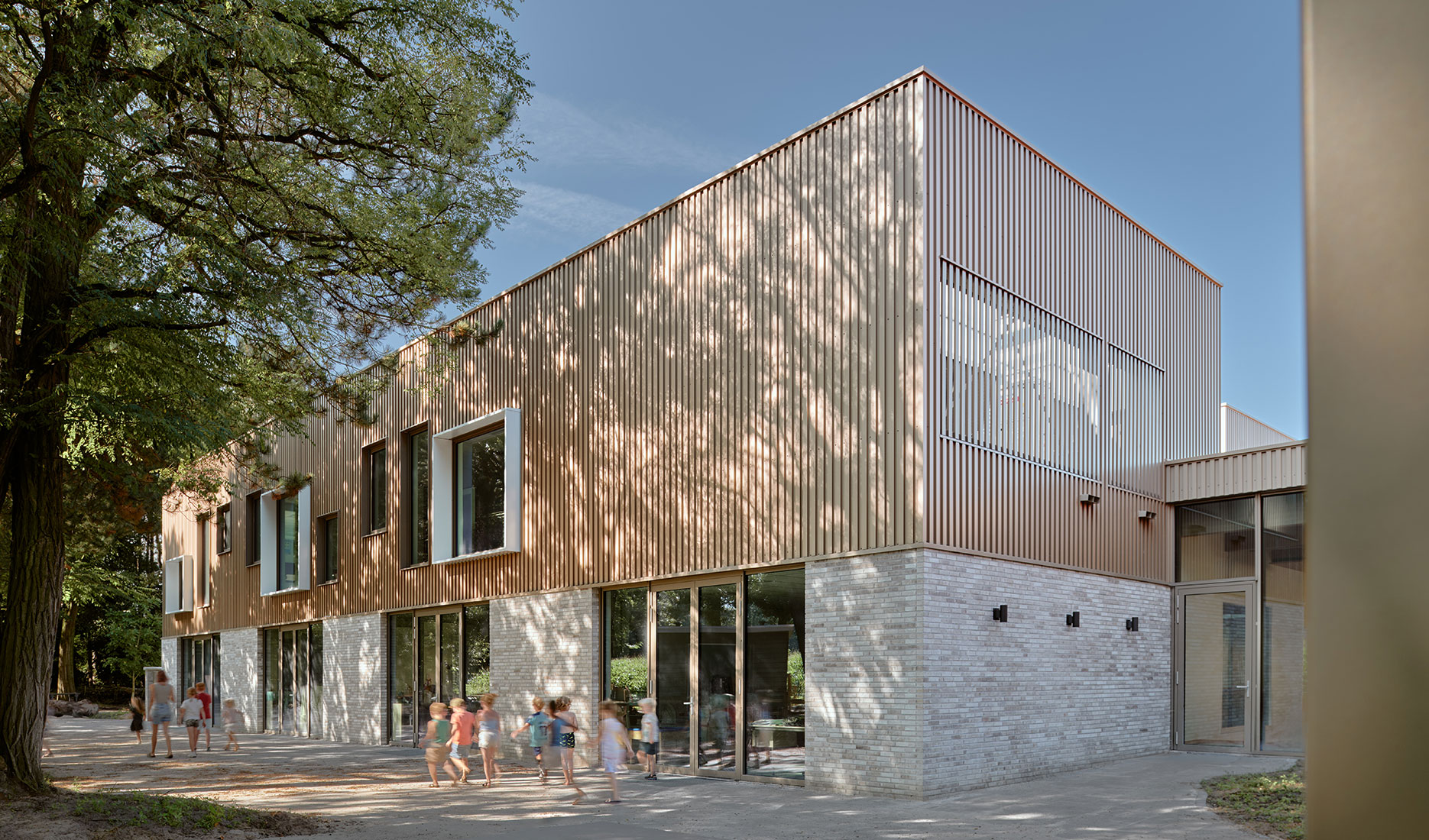 Modern school building with wood facade and large windows, children walking outside