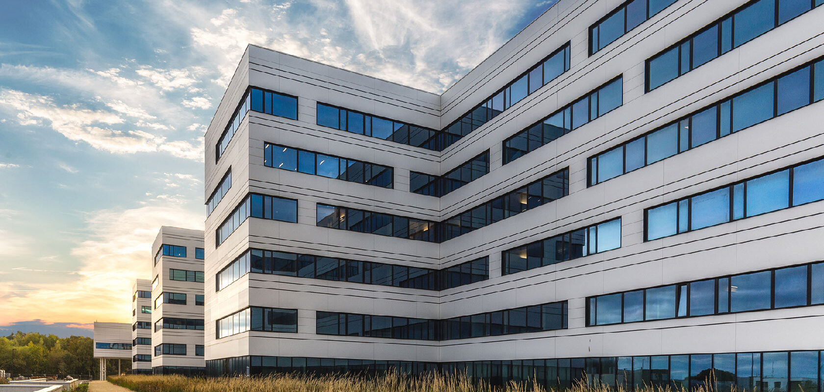 Modern hospital building exterior with glass windows at sunset sky
