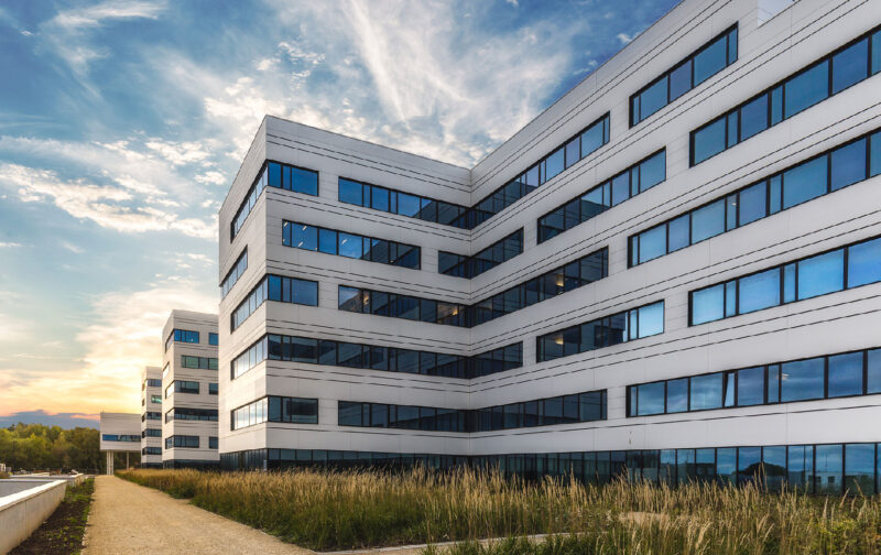 Modern hospital building exterior with glass windows at sunset sky