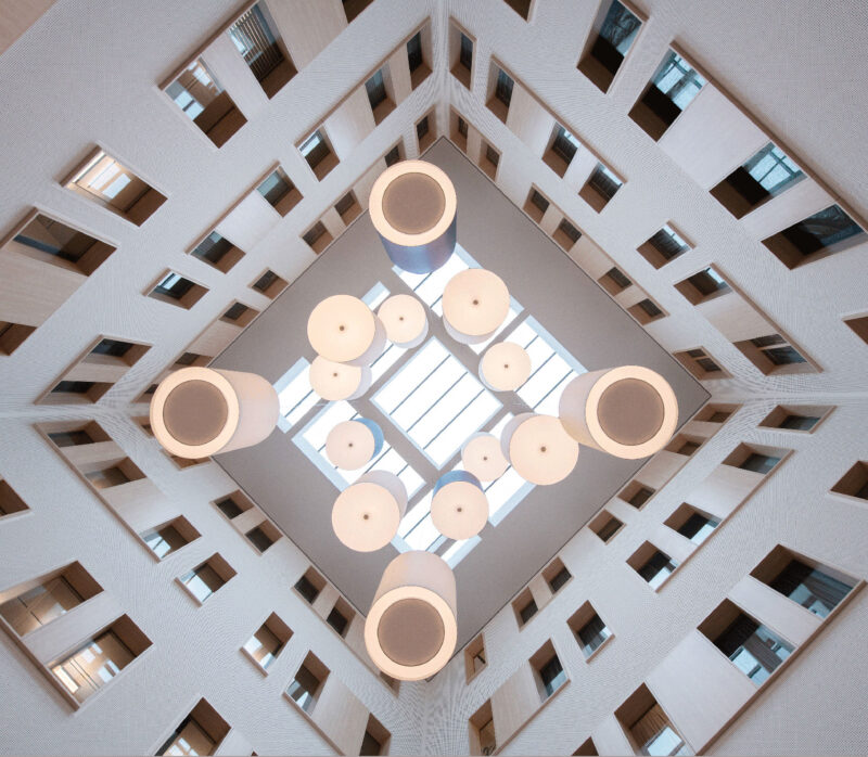 Modern building atrium ceiling with skylight and circular pendant lights, geometric view upward