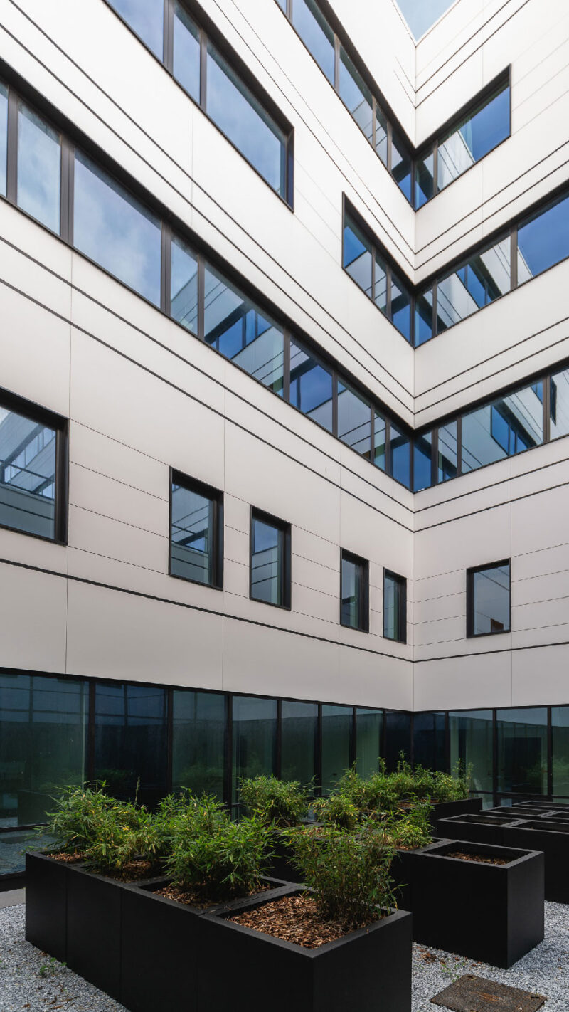 Modern hospital building courtyard with glass windows and rooftop planters