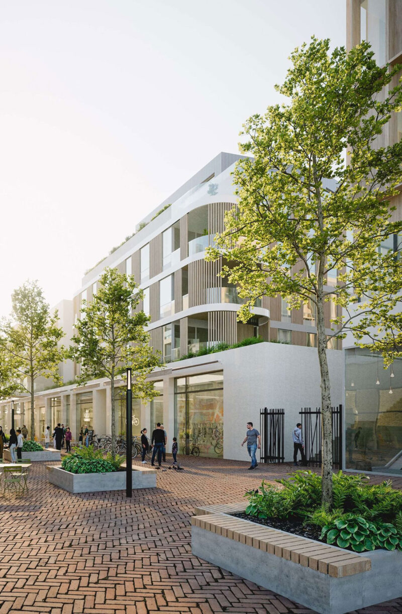 Modern mixed-use building with tree-lined pedestrian plaza and shops at street level