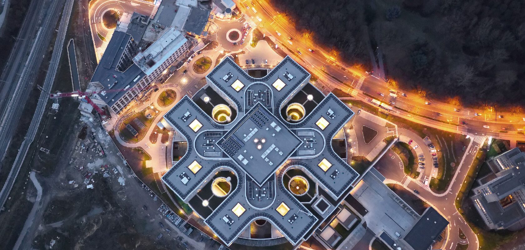 Aerial night view of modern hospital complex with illuminated roads and roundabouts