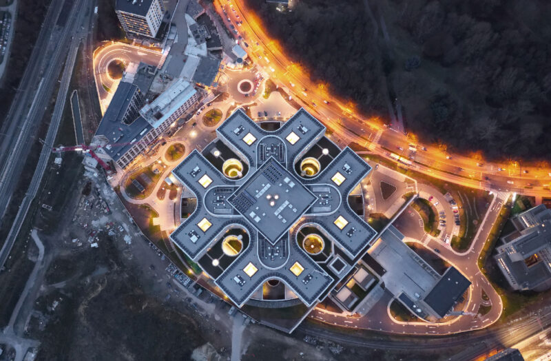 Aerial night view of modern hospital complex with illuminated roads and roundabouts