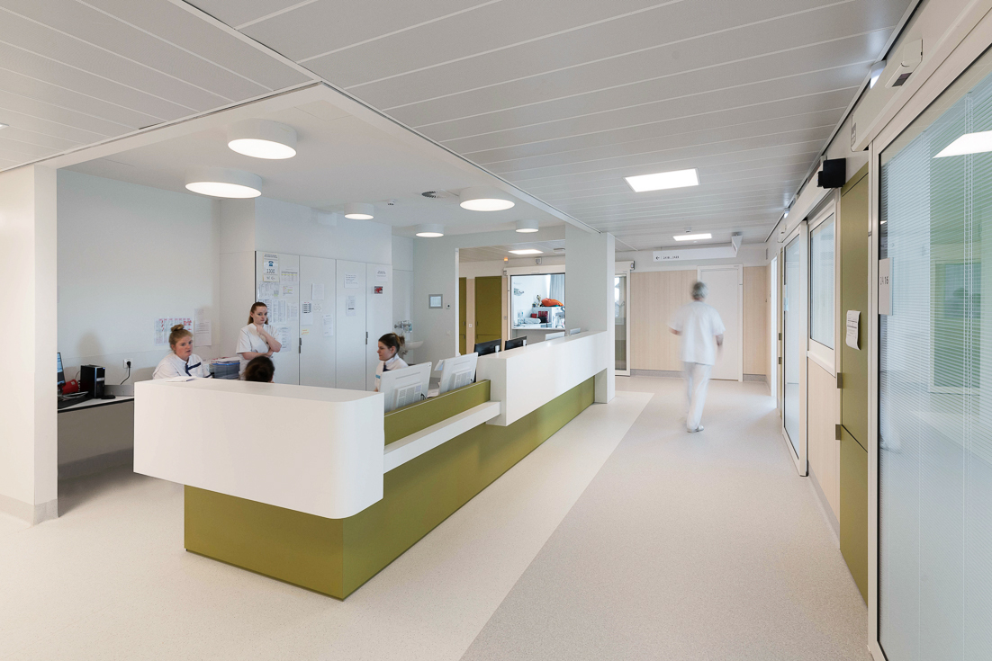 Modern hospital nurse station with staff at reception desk in bright clinic corridor