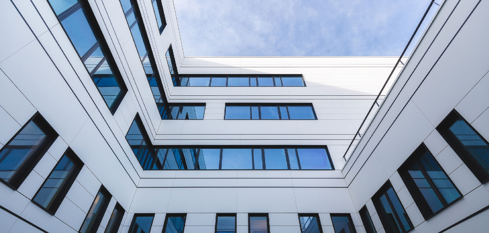 Modern hospital building courtyard with blue glass windows and white facade, upward view