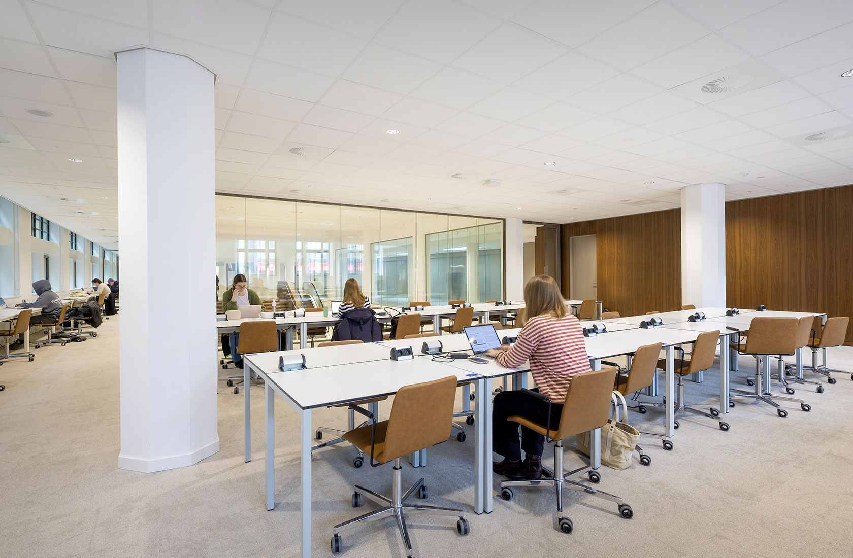 Students working on laptops in a modern university library study room