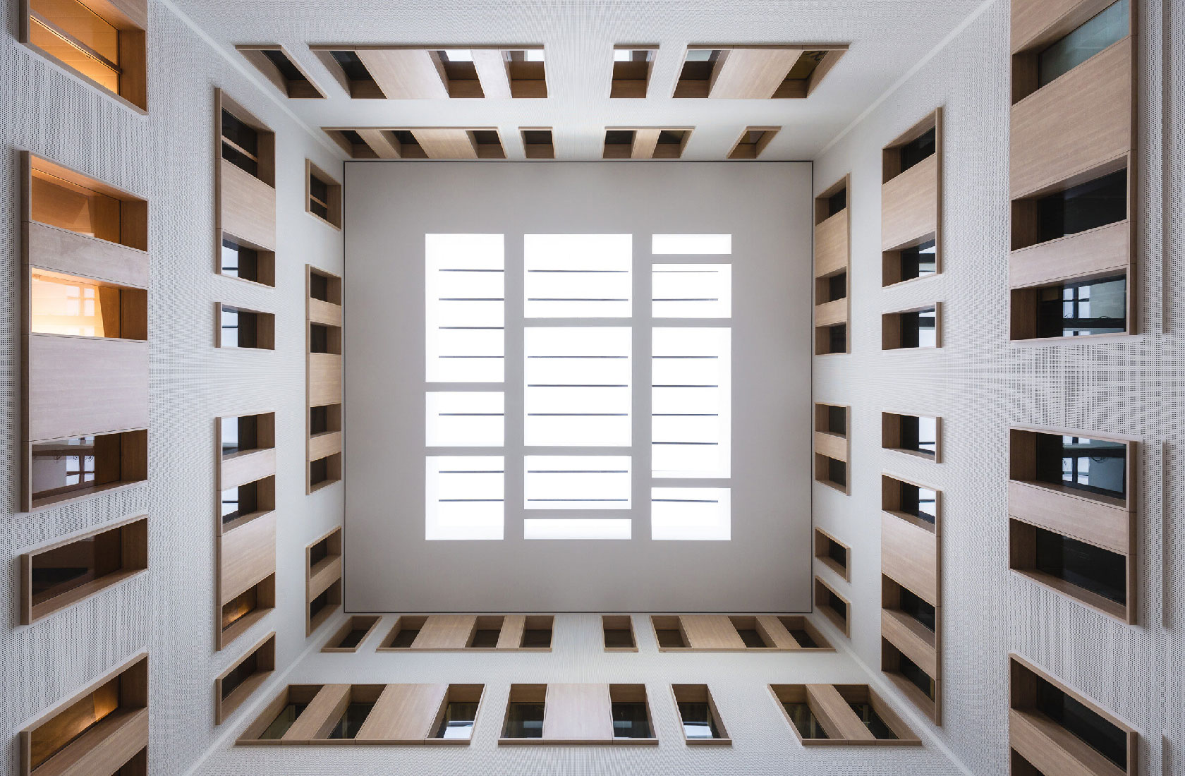 Upward view of modern hospital building atrium with skylight and geometric windows