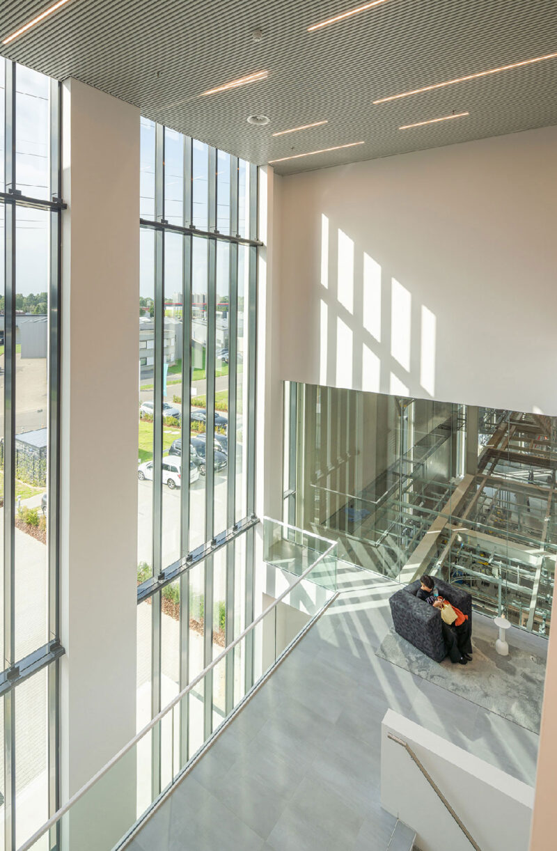 Modern industrial warehouse entrance with glass facade and loading dock under blue sky.