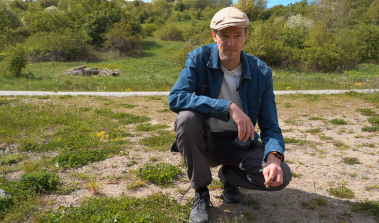 Man sittande på huk på en gräsmatta