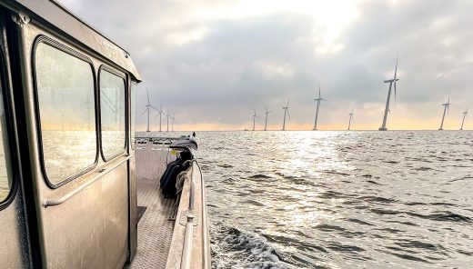 Båt på havet med vindkraftverk i förgrunden